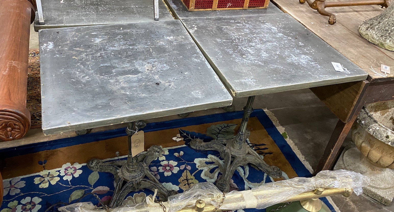 A pair of zinc topped cafe tables with cast iron bases, width 60cm depth 60cm height 74cm